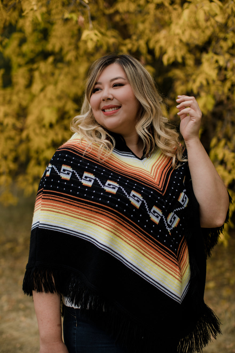 woman in yellow and orange poncho smiles