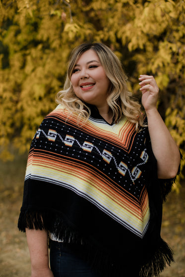 woman in yellow and orange poncho smiles