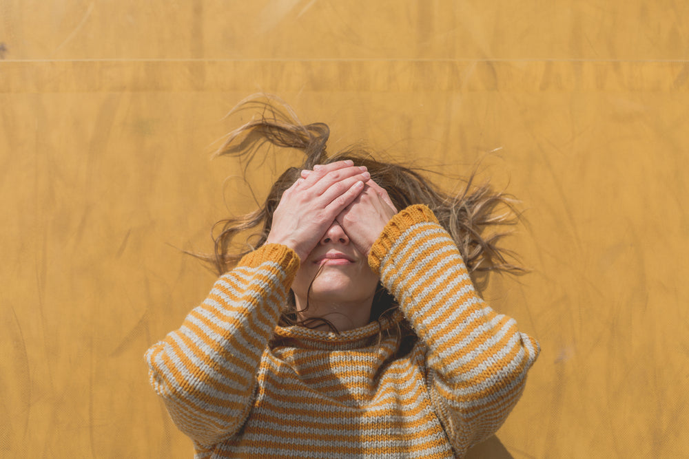 woman in yellow hides face