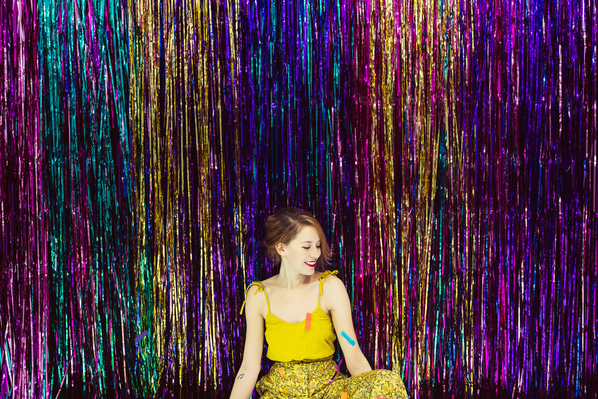 woman in yellow smiles against a backdrop of streamers