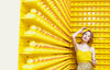 woman in yellow stands before a wall of rubber ducks