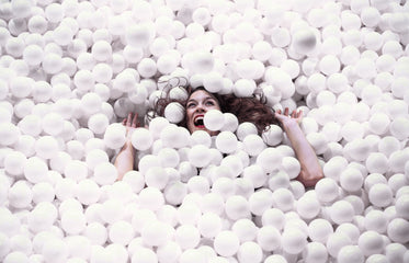 woman is swallowed up by a pool of styrofoam balls