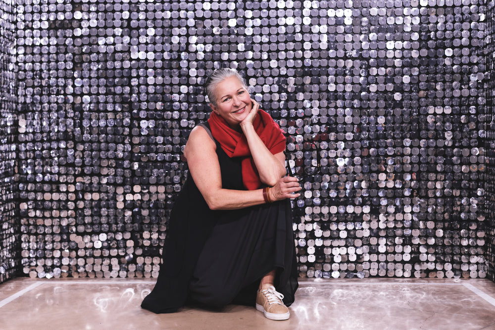 woman kneels in front of silver backdrop