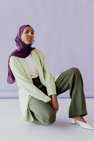 woman kneels in green and purple