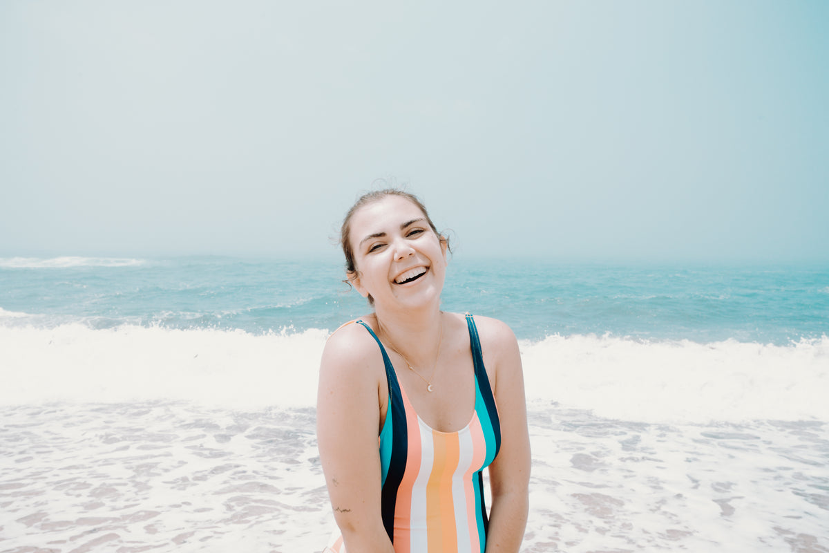 woman laughing by aqua blue ocean water