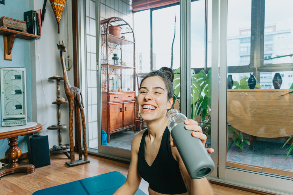 woman laughs and holds up water bottle to drink