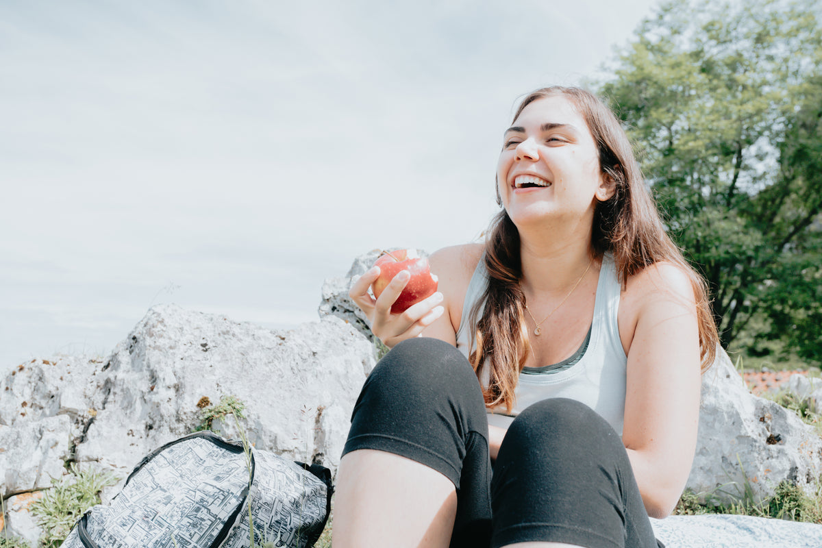 woman laughs while sitting outdoors on rocks