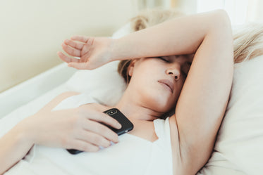 woman lays in bed with hand over her eyes