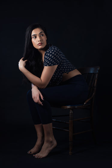 woman leaning forward while sitting on wooden chair