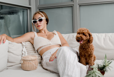 woman leans back on a white couch with a small puppy