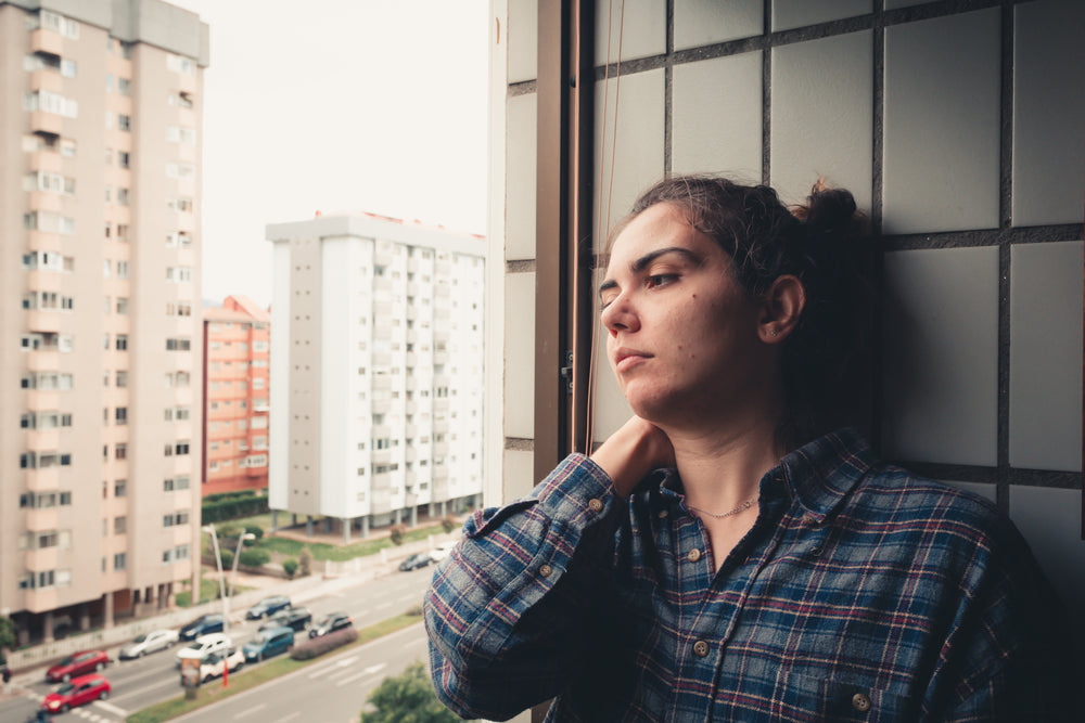 woman leans on a tiled wall and looks out the window