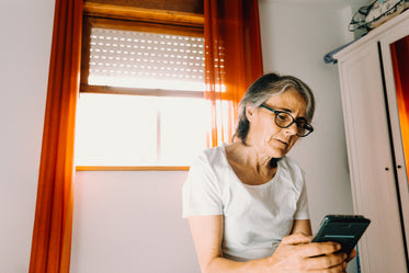 woman looks at her cell phone near a bright window