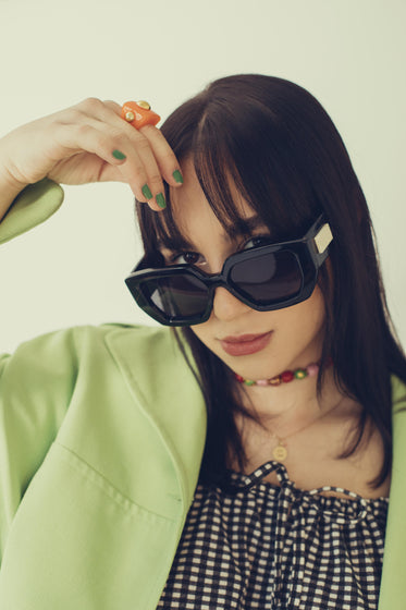 woman looks at the camera over bold black sunglasses