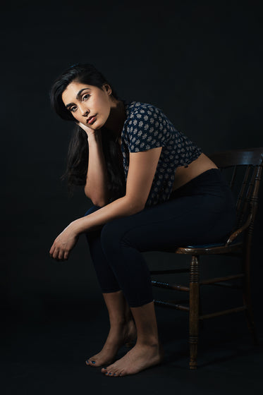 woman looks forward while sitting on wooden chair