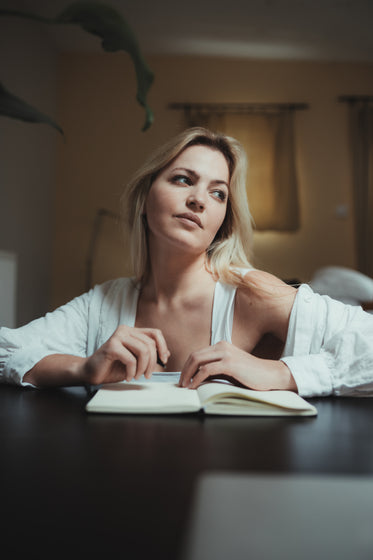 woman looks up in deep thought as she journals
