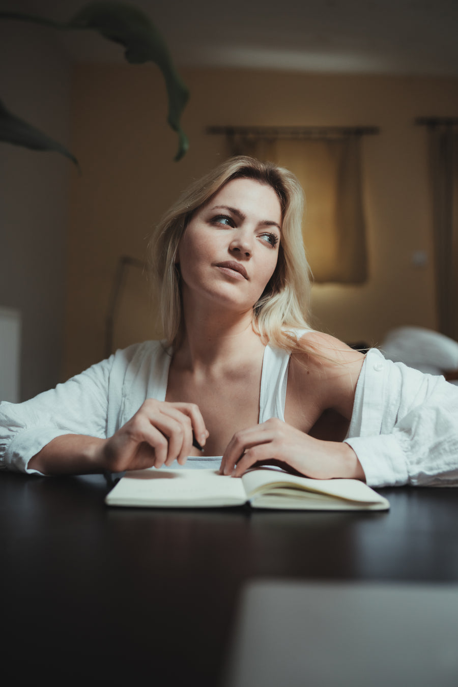 A woman pausing in thought while writing in a journal