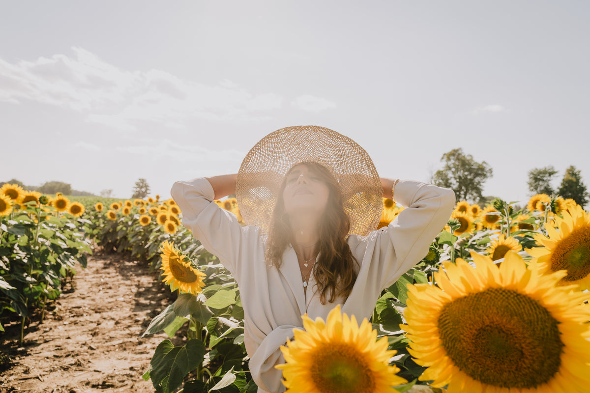 woman looks up standing in a field of sunflowers