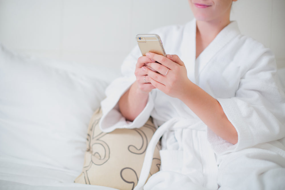 woman lounges in bathrobe with phone