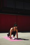 woman lunges forwards on a pink yoga mat