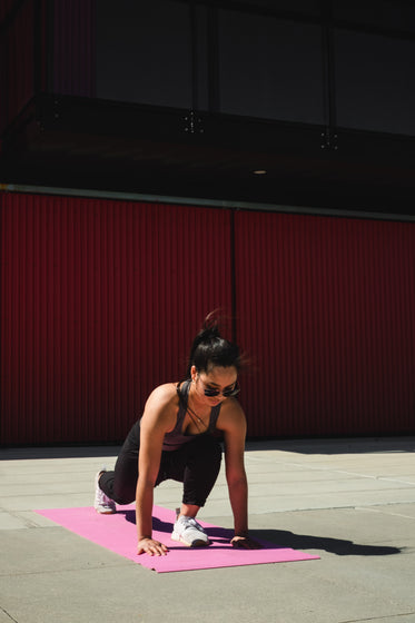 woman lunges forwards on a pink yoga mat