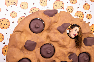 woman makes eye contact through a giant chocolate chip cookie