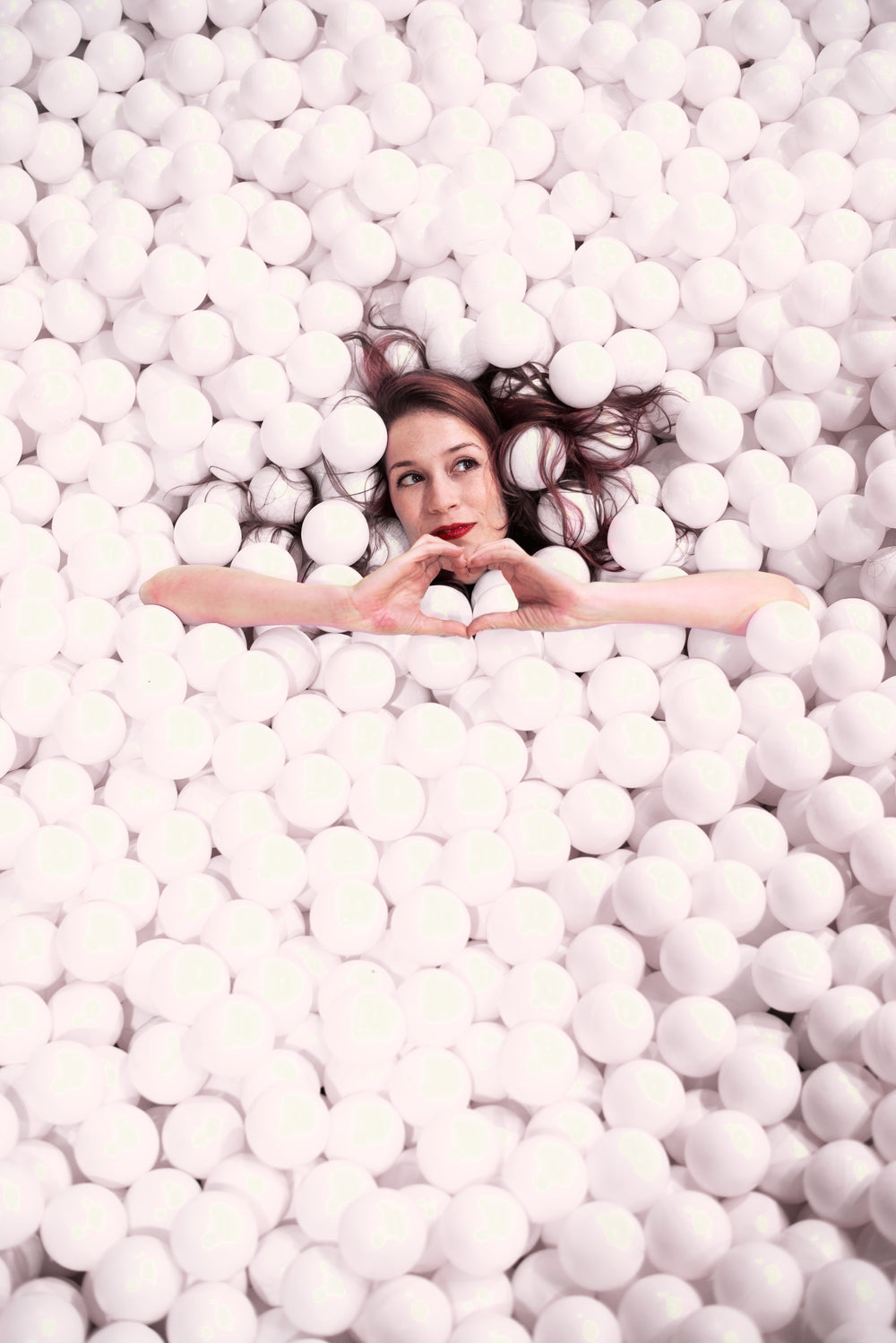 woman makes the hand heart gesture while covered styrofoam balls
