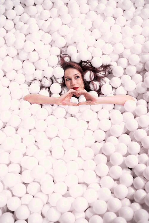 woman makes the hand heart gesture while covered styrofoam balls