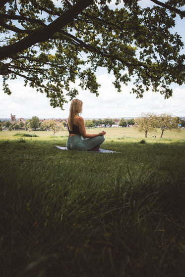 woman meditates cross legged under a tree
