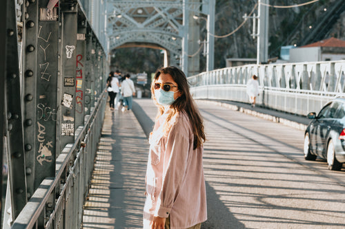 woman on a bridge in a facemask