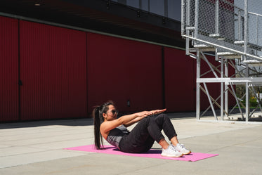 woman on a pink yoga mat crunches forward