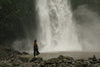 woman pauses at foot of waterfall