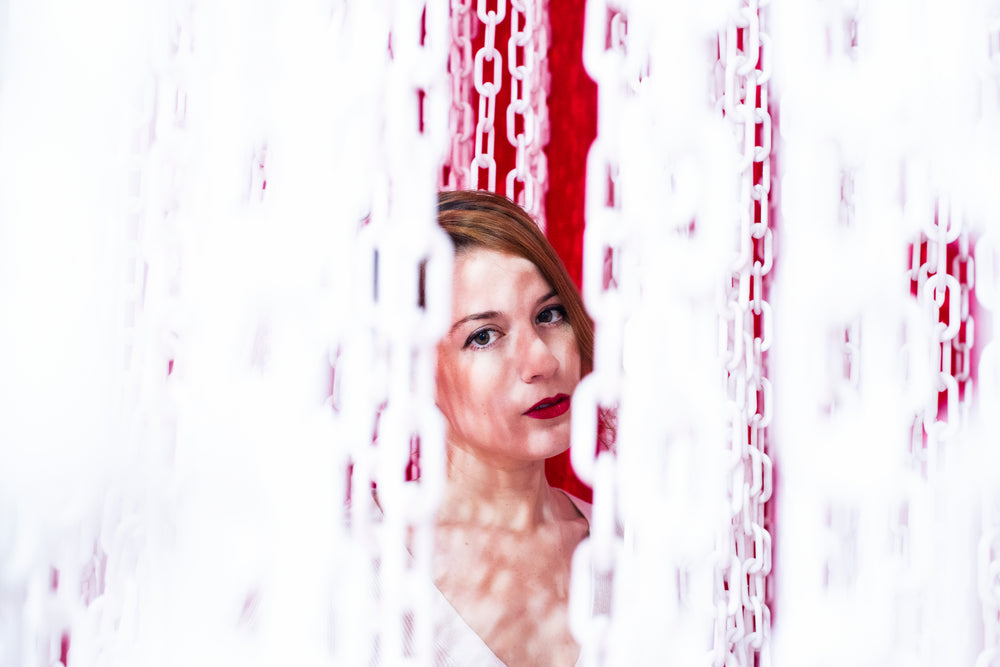 woman peering out from a curtain of chains