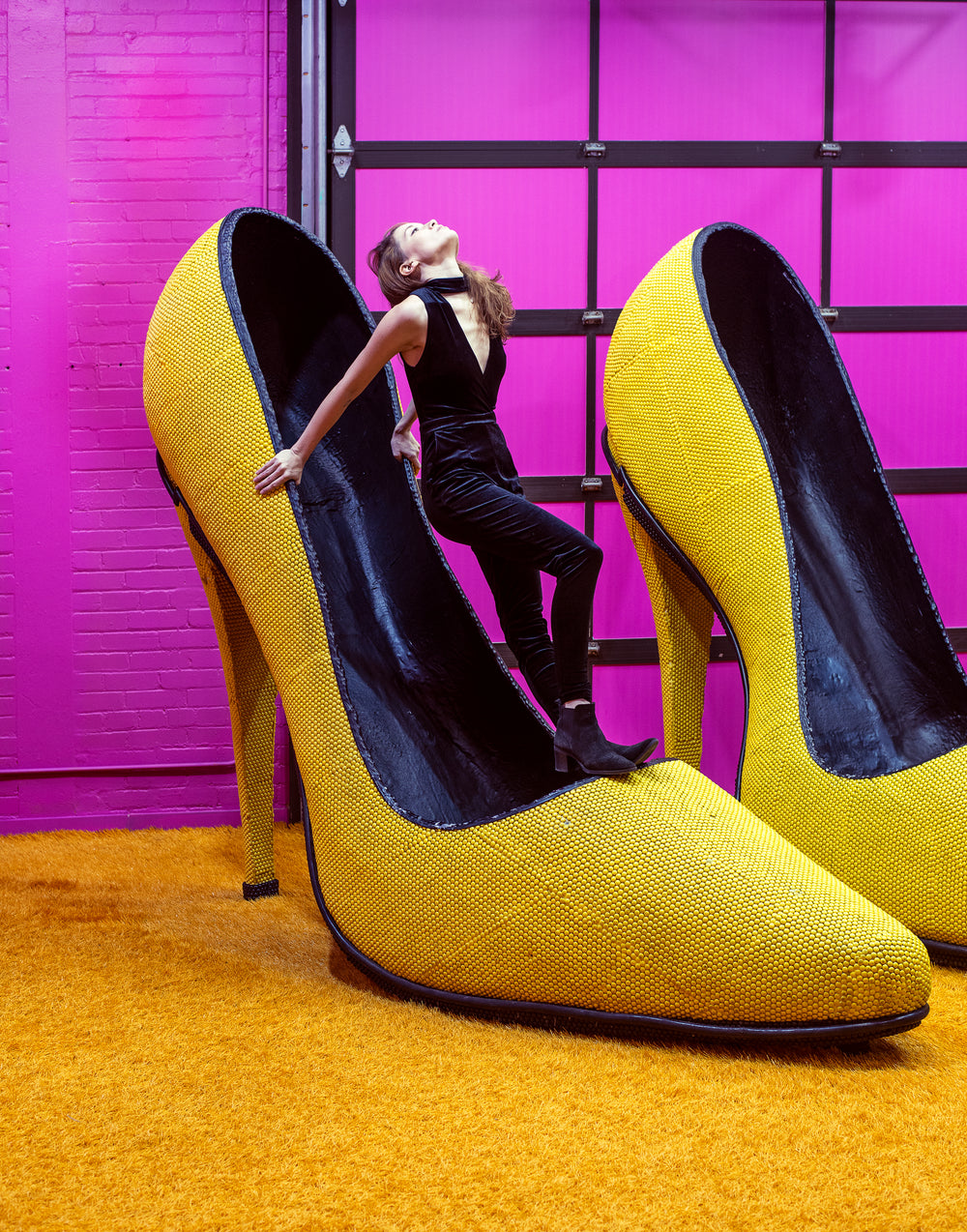 woman perches atop a giant shoe facing the ceiling