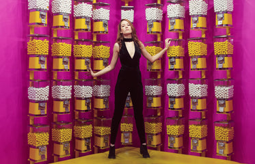 woman poses against a wall of gumball machines
