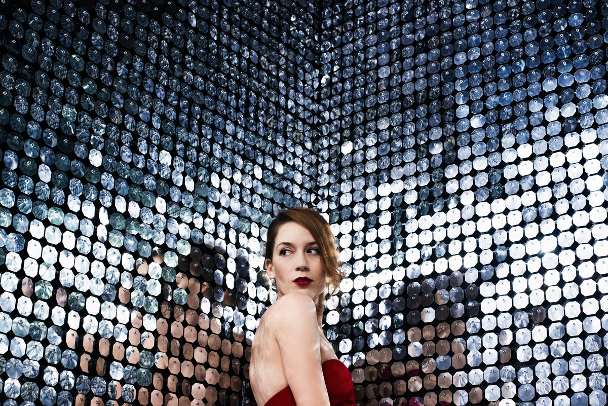 woman poses in the corner of a room of mirrors