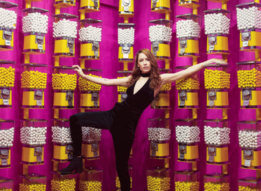 woman poses with a wall of gumball machines