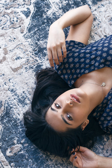 woman poses with her hands on patterned rug