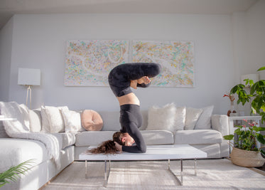 woman practices advanced yoga pose on coffee table