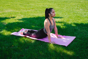 woman practices yoga in green grass