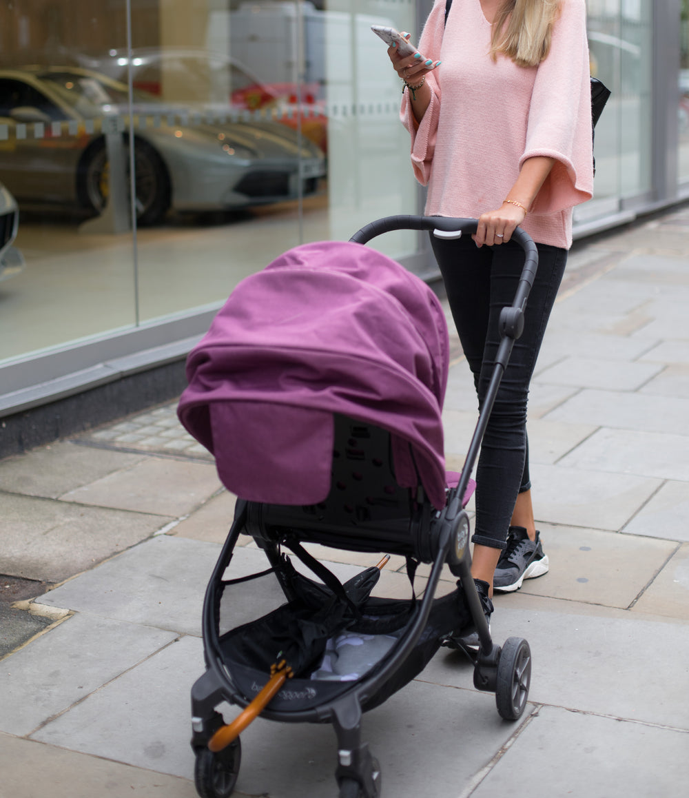 woman pushes stroller while using phone