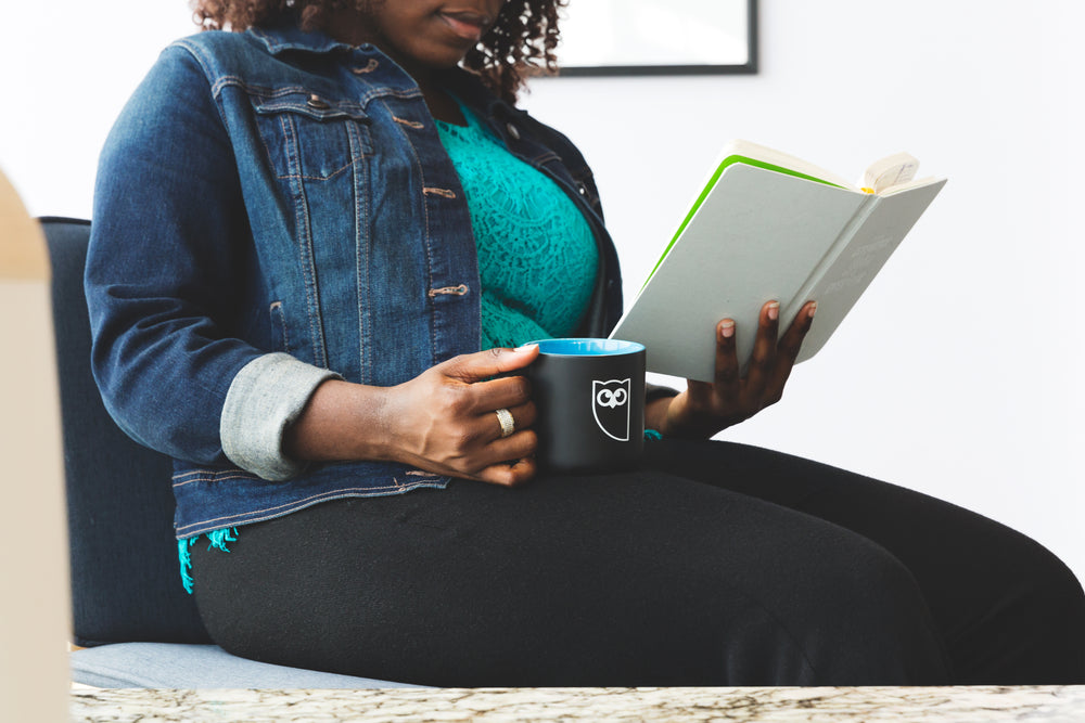 woman reading and drinking coffee from mug