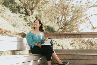 woman reads a book on a bench outdoors