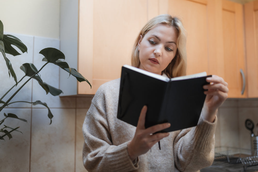 woman reads a novel in her kitchen