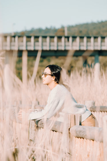 woman rests on a wooden fence outdoors