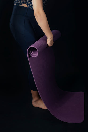 woman rolls yoga mat
