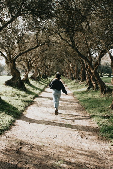 woman runs down a tree lined pathway