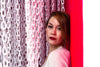 woman sandwiched between a red wall and a curtain of white chains