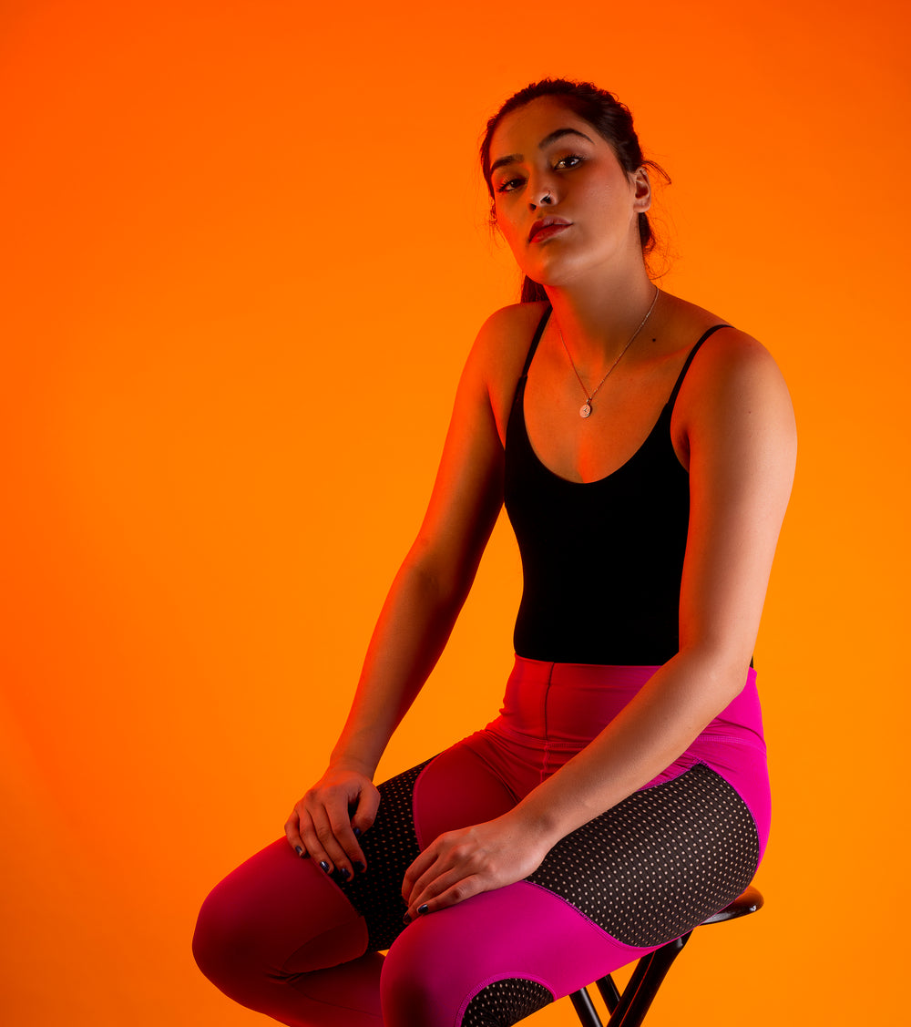 woman sits against orange