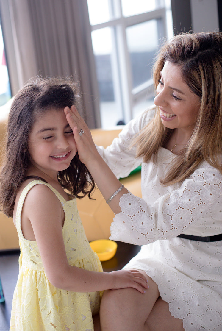Woman Sits And Pulls The Hair Back From A Childs Face