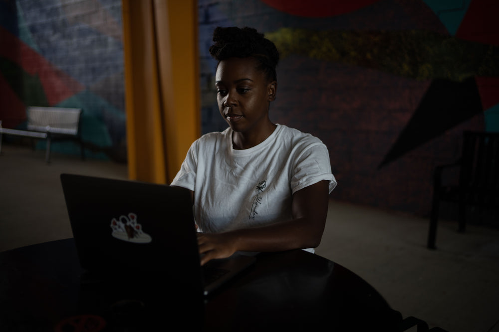 woman sits and works on an open laptop